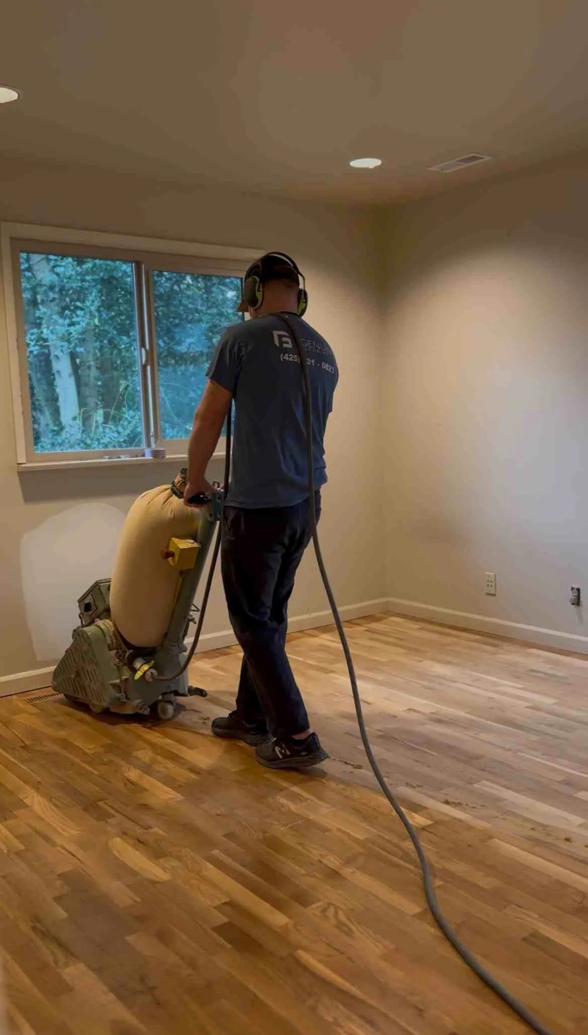 Hardwood floor sanding with industrial drum sander equipment in residential room