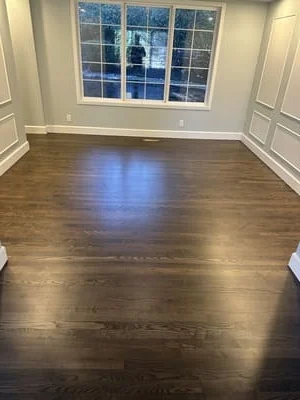 Dark hardwood flooring with satin finish in room with white trim and large windows