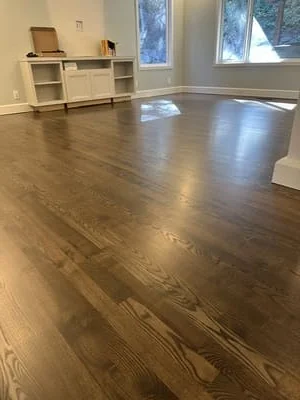 Newly finished hardwood floor with medium-brown stain and glossy finish in empty room