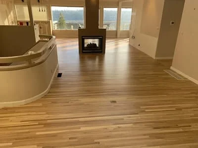 Engineered hardwood flooring in warm oak tone installed in open living space with fireplace