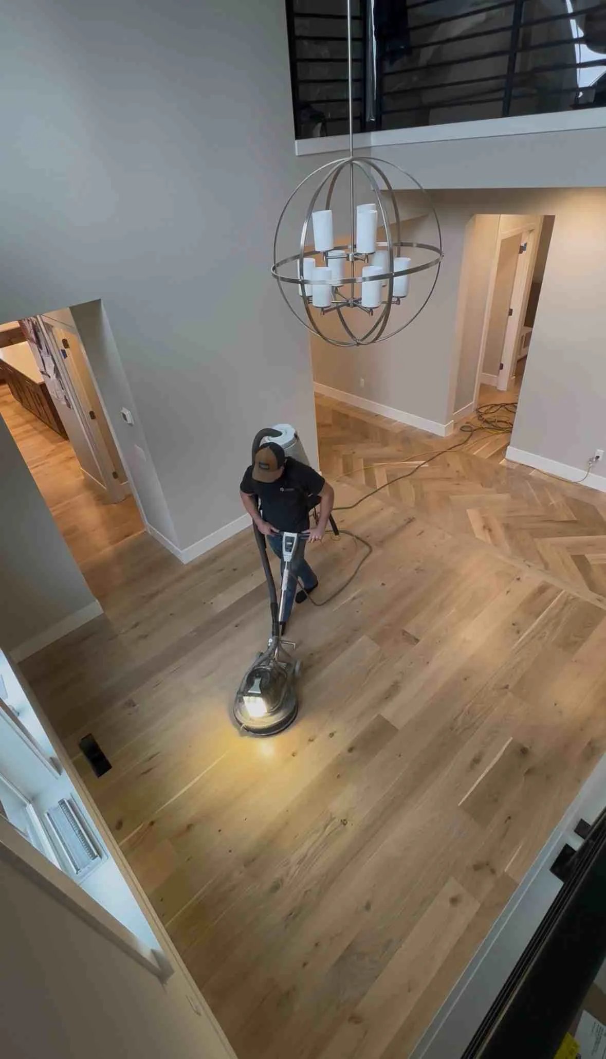 Hardwood floor installation in herringbone pattern with natural wood finish and professional sanding equipment
