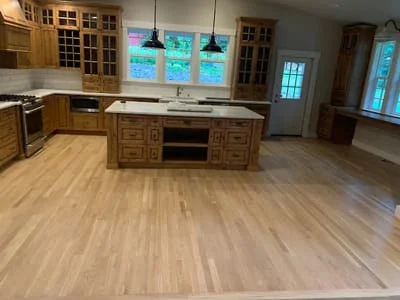Wide-plank hardwood flooring in light oak finish installed in kitchen with custom wood cabinetry