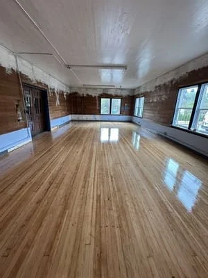 Newly installed hardwood flooring with satin finish in large open room with windows