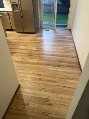 Newly installed hardwood flooring with warm wood tones in kitchen and entryway area