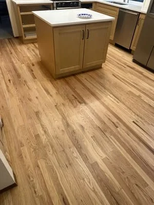 Luxury vinyl plank flooring with wood-tone finish installed in kitchen with wooden cabinetry and island