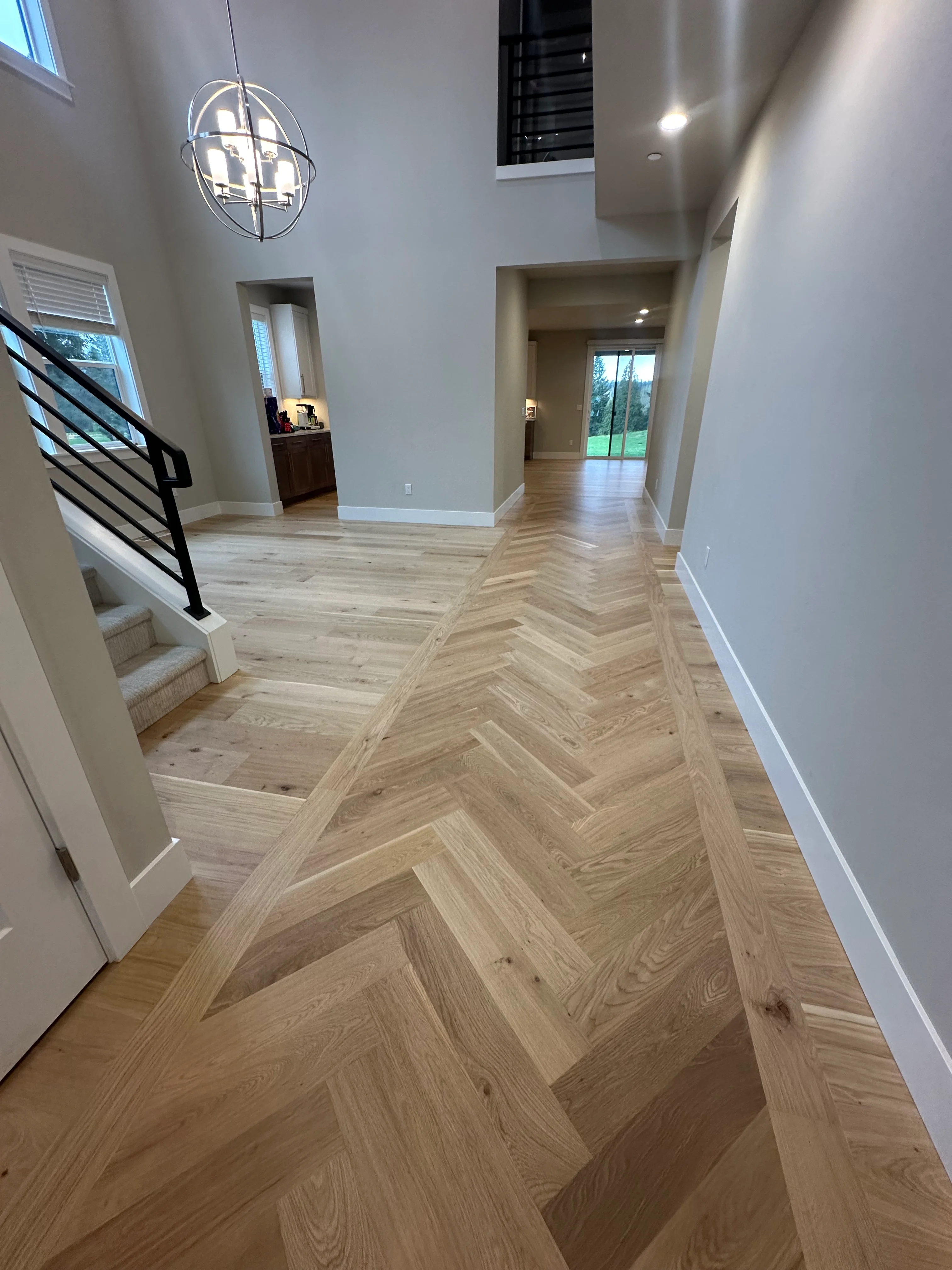 Herringbone pattern hardwood flooring in light oak throughout modern entryway and hallway